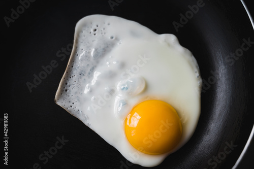 The egg is fried in a frying pan without oil. Healthy breakfast. Close-up. View from above.