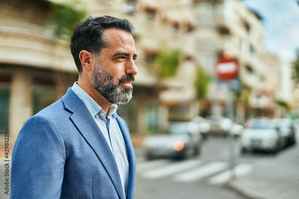 Naklejka premium Middle age businessman with relaxed expression standing at the city.