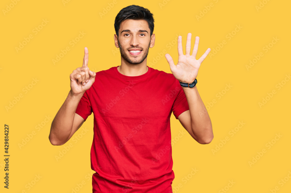 Young handsome man wearing casual red tshirt showing and pointing up with fingers number six while smiling confident and happy. Young handsome man wearing casual red tshirt showing and pointing up with fingers number six while smiling confident and happy.