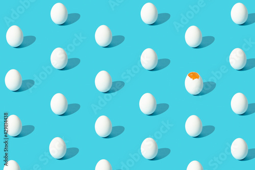 White eggs pattern (broken and whole) on a blue background viewed from above. Copy space