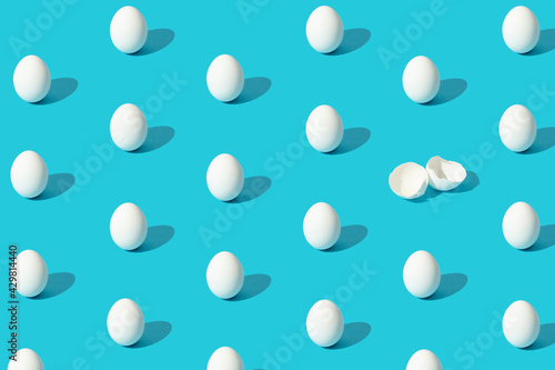 White eggs pattern (broken and whole) on a blue background viewed from above.  Copy space