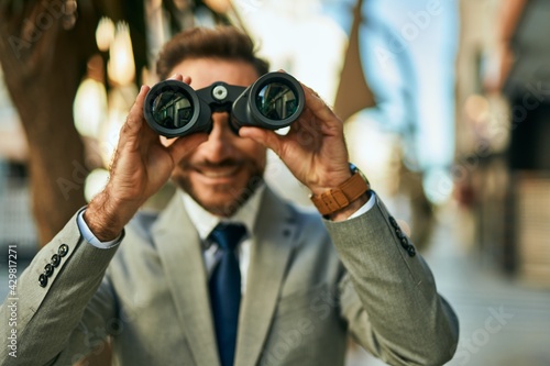 Middle age businessman looking for new opportunity using binoculars at the city. photo