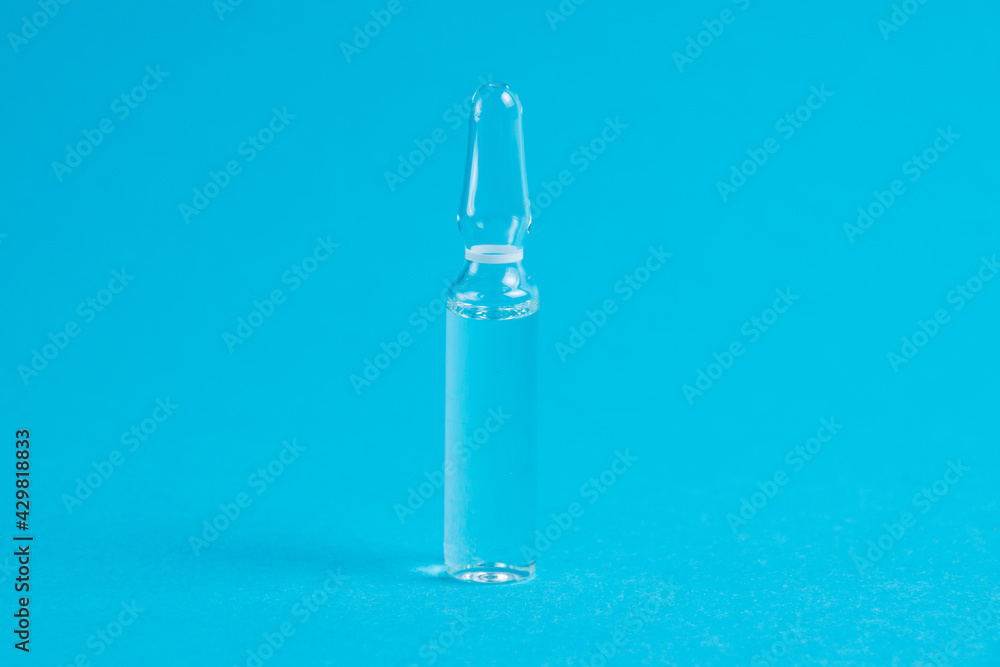 Ampoule with medicine on a blue background close-up macro, copy space. Treatment concept for coronavirus patients Ampoule with medicine on a blue background close-up macro, copy space. Treatment concept for coronavirus patients
