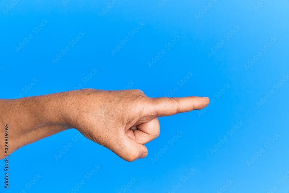Hand of senior hispanic man over blue isolated background pointing with index finger to the side, suggesting and selecting a choice