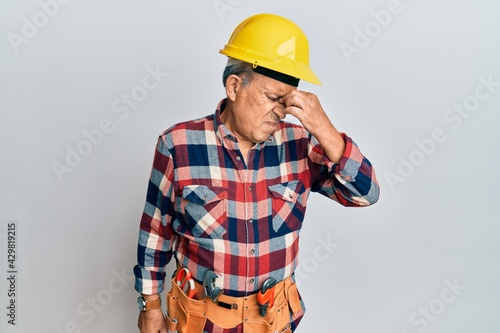 Senior hispanic man wearing handyman uniform tired rubbing nose and eyes feeling fatigue and headache. stress and frustration concept.