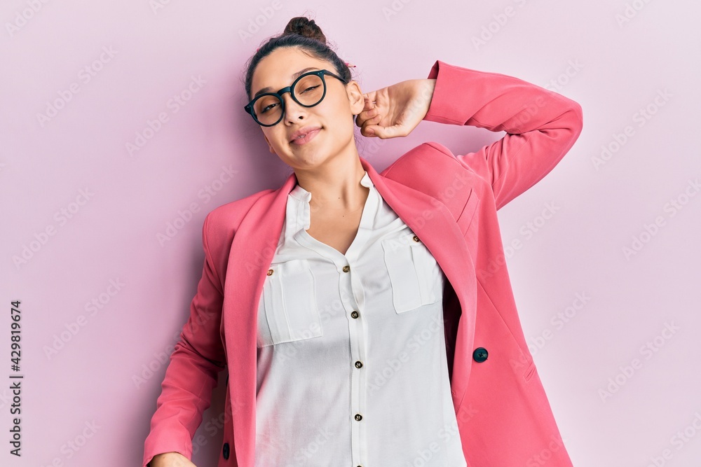 Beautiful middle eastern woman wearing business jacket and glasses stretching back, tired and relaxed, sleepy and yawning for early morning