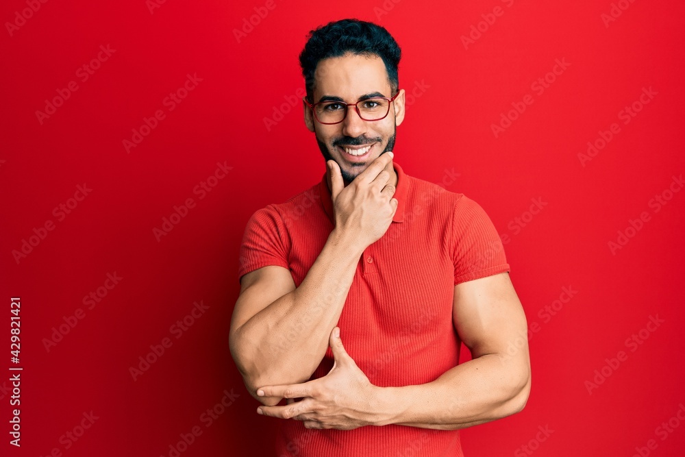 Young hispanic man wearing casual clothes and glasses looking confident at the camera smiling with crossed arms and hand raised on chin. thinking positive. Young hispanic man wearing casual clothes and glasses looking confident at the camera smiling with crossed arms and hand raised on chin. thinking positive.