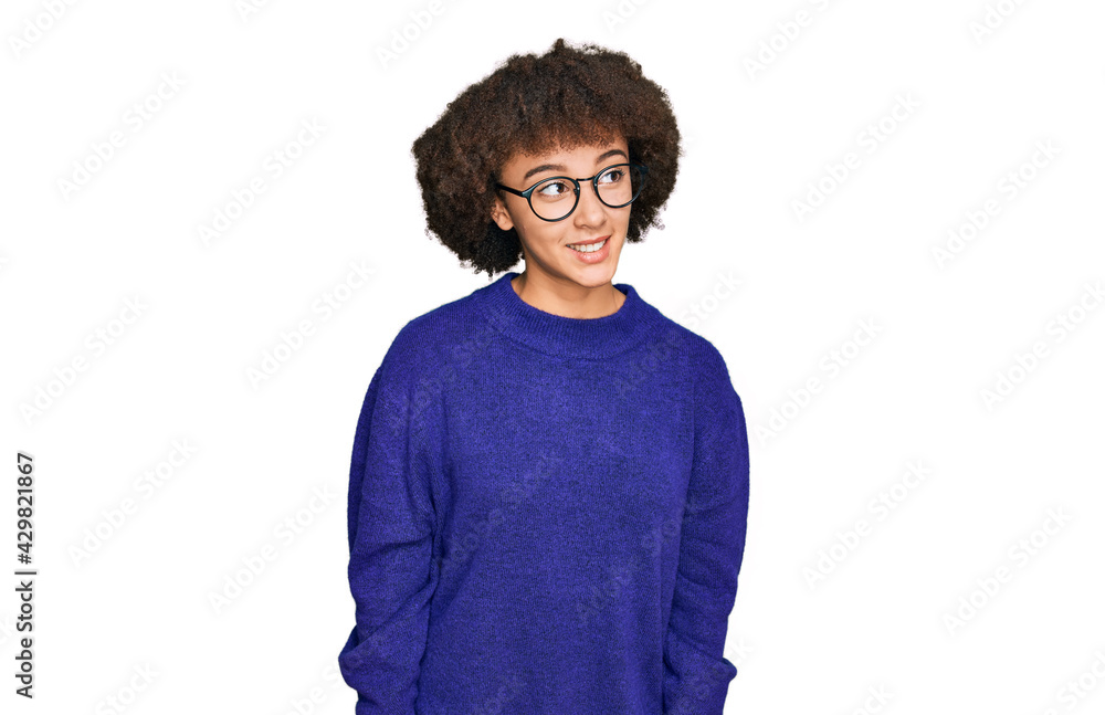 Young hispanic girl wearing casual winter sweater and glasses looking away to side with smile on face, natural expression. laughing confident. Young hispanic girl wearing casual winter sweater and glasses looking away to side with smile on face, natural expression. laughing confident.