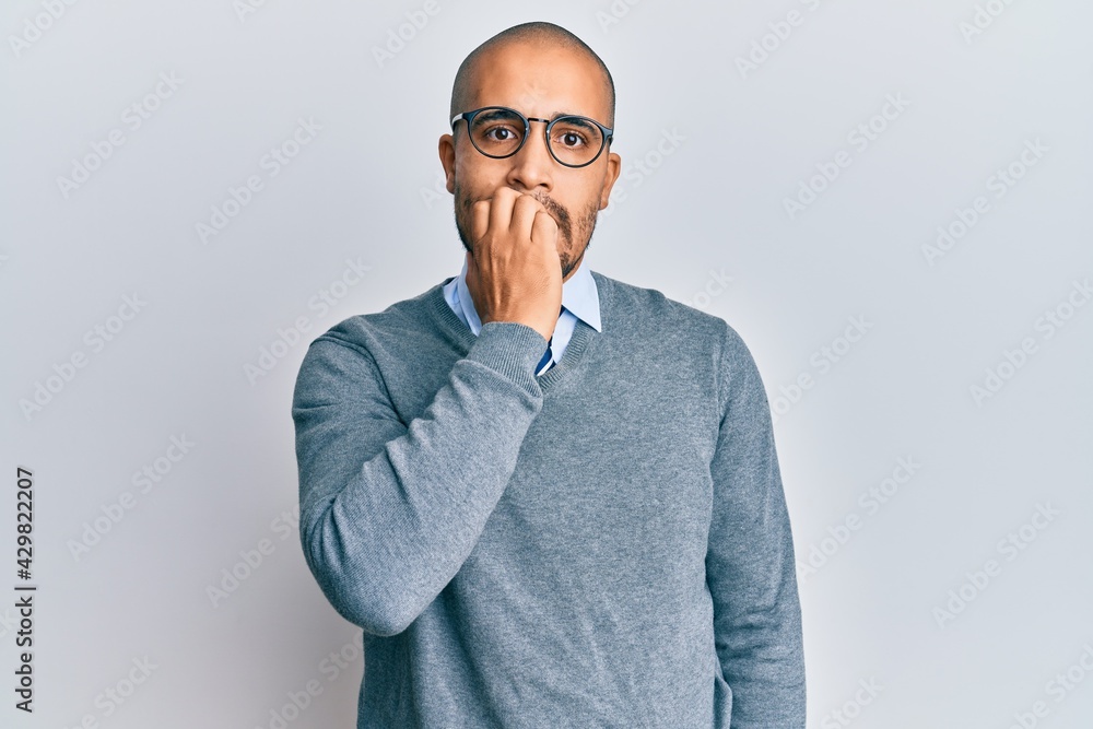 Hispanic adult man wearing glasses and business style looking stressed and nervous with hands on mouth biting nails. anxiety problem. Hispanic adult man wearing glasses and business style looking stressed and nervous with hands on mouth biting nails. anxiety problem.