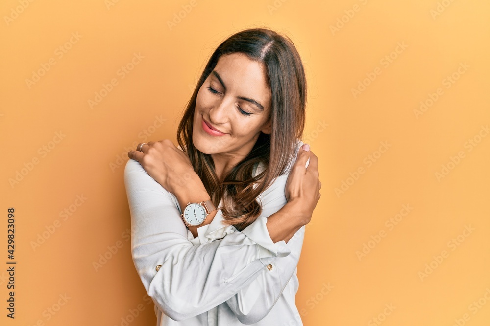 Young beautiful woman wearing casual clothes hugging oneself happy and positive, smiling confident. self love and self care
