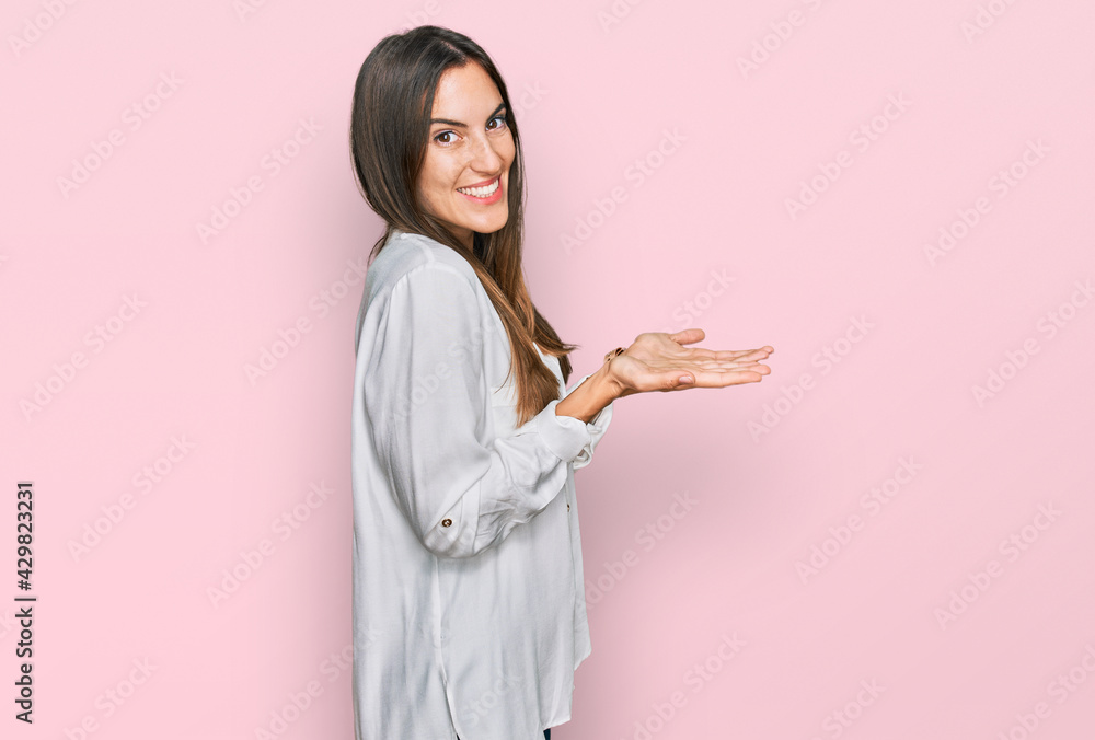 Young beautiful woman wearing casual clothes pointing aside with hands open palms showing copy space, presenting advertisement smiling excited happy Young beautiful woman wearing casual clothes pointing aside with hands open palms showing copy space, presenting advertisement smiling excited happy