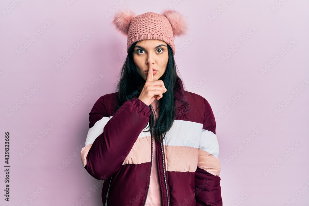 Young hispanic woman wearing wool winter sweater and cap asking to be quiet with finger on lips. silence and secret concept. Young hispanic woman wearing wool winter sweater and cap asking to be quiet with finger on lips. silence and secret concept.