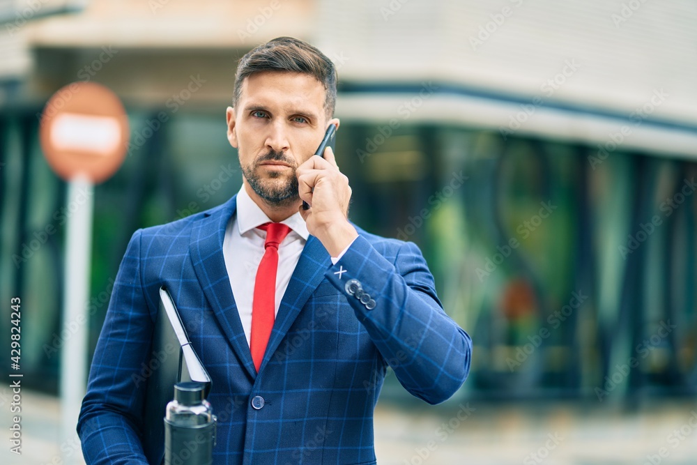Young caucasian businessman with serious expression talking on the smartphone at the city. Young caucasian businessman with serious expression talking on the smartphone at the city.