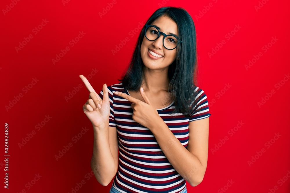 Beautiful asian young woman wearing casual clothes and glasses smiling and looking at the camera pointing with two hands and fingers to the side. Beautiful asian young woman wearing casual clothes and glasses smiling and looking at the camera pointing with two hands and fingers to the side.