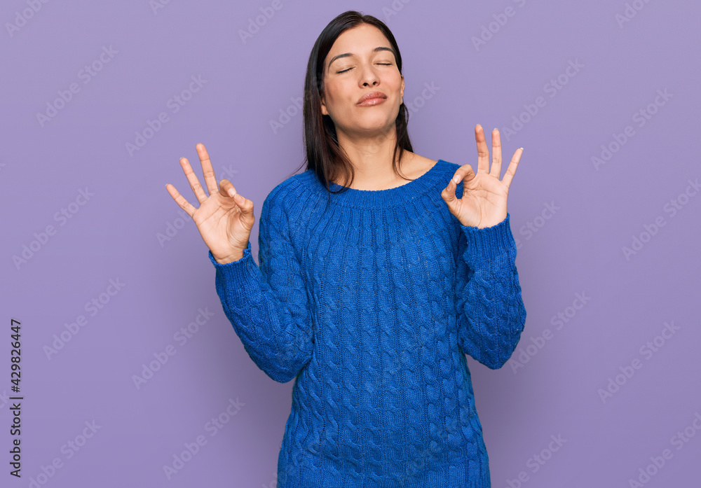 Young hispanic woman wearing casual clothes relaxed and smiling with eyes closed doing meditation gesture with fingers. yoga concept. Young hispanic woman wearing casual clothes relaxed and smiling with eyes closed doing meditation gesture with fingers. yoga concept.