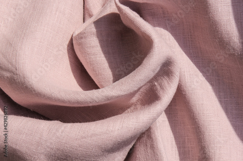 The pink linen fabric is draped. Linen is a natural and environmentally friendly material.