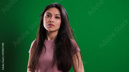 Young pretty woman in the studio posing against a green background - studio photography