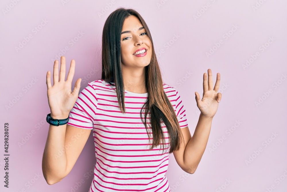 Young brunette woman wearing casual clothes over pink background showing and pointing up with fingers number nine while smiling confident and happy. Young brunette woman wearing casual clothes over pink background showing and pointing up with fingers number nine while smiling confident and happy.