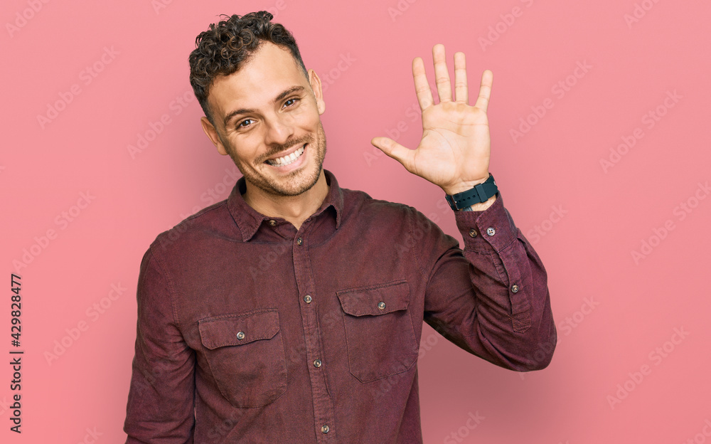 Young hispanic man wearing casual clothes waiving saying hello happy and smiling, friendly welcome gesture Young hispanic man wearing casual clothes waiving saying hello happy and smiling, friendly welcome gesture