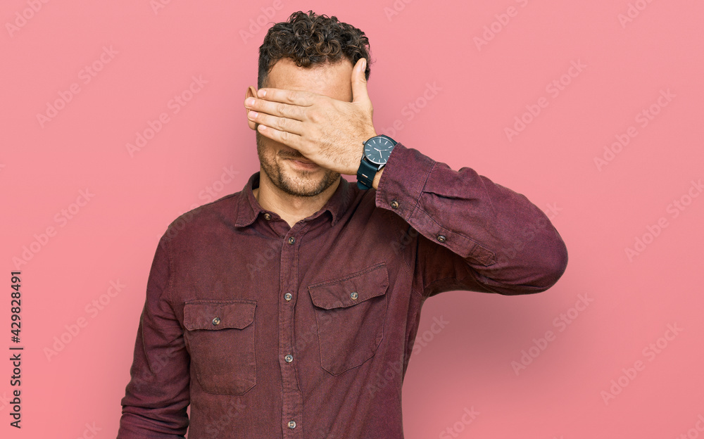 Young hispanic man wearing casual clothes covering eyes with hand, looking serious and sad. sightless, hiding and rejection concept Young hispanic man wearing casual clothes covering eyes with hand, looking serious and sad. sightless, hiding and rejection concept