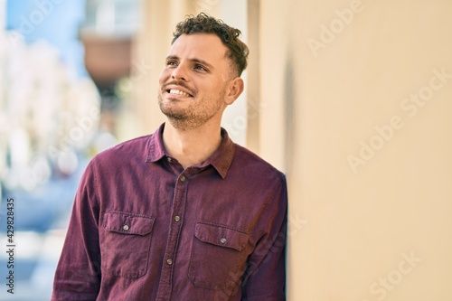 Young hispanic man smiling happy standing at the city.