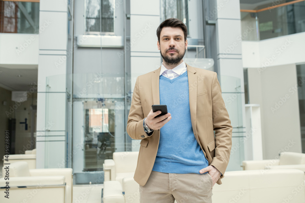 Bearded lawyer checking smartphone in lobby