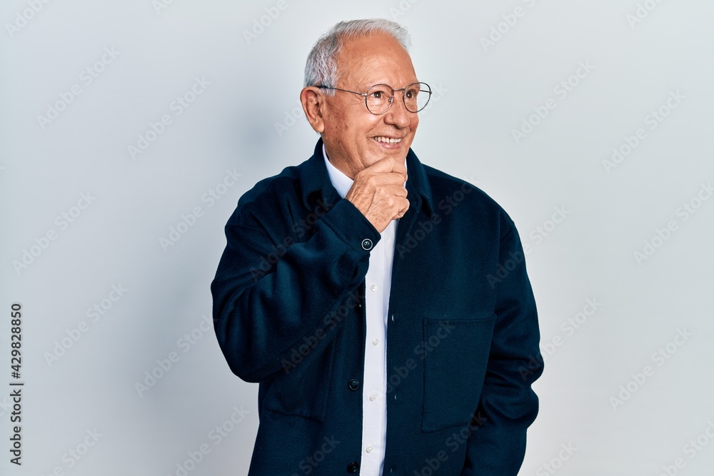 Senior man with grey hair wearing casual style and glasses with hand on chin thinking about question, pensive expression. smiling with thoughtful face. doubt concept. Senior man with grey hair wearing casual style and glasses with hand on chin thinking about question, pensive expression. smiling with thoughtful face. doubt concept.