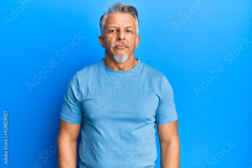 Middle age grey-haired man wearing casual clothes relaxed with serious expression on face. simple and natural looking at the camera.