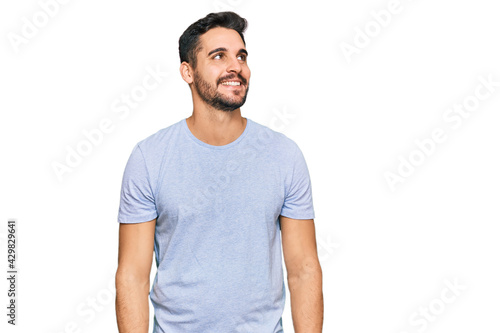 Young hispanic man wearing casual clothes looking away to side with smile on face, natural expression. laughing confident.