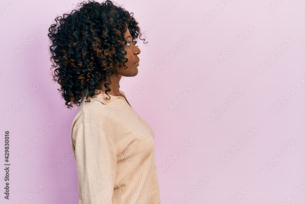 Young african american woman wearing casual clothes looking to side, relax profile pose with natural face with confident smile. Young african american woman wearing casual clothes looking to side, relax profile pose with natural face with confident smile.