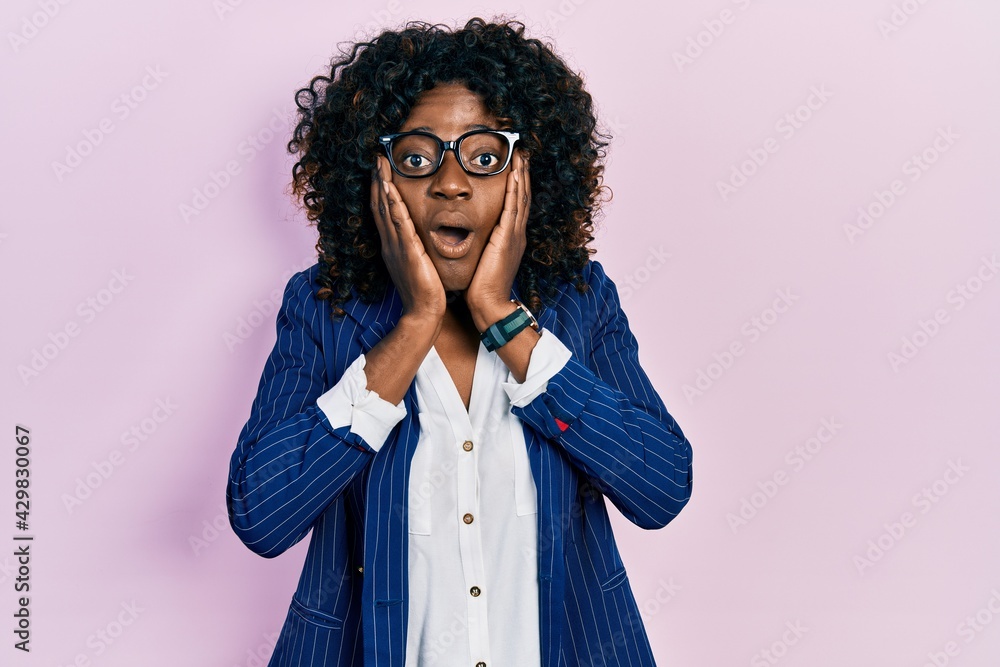 Young african american woman wearing business clothes and glasses afraid and shocked, surprise and amazed expression with hands on face Young african american woman wearing business clothes and glasses afraid and shocked, surprise and amazed expression with hands on face