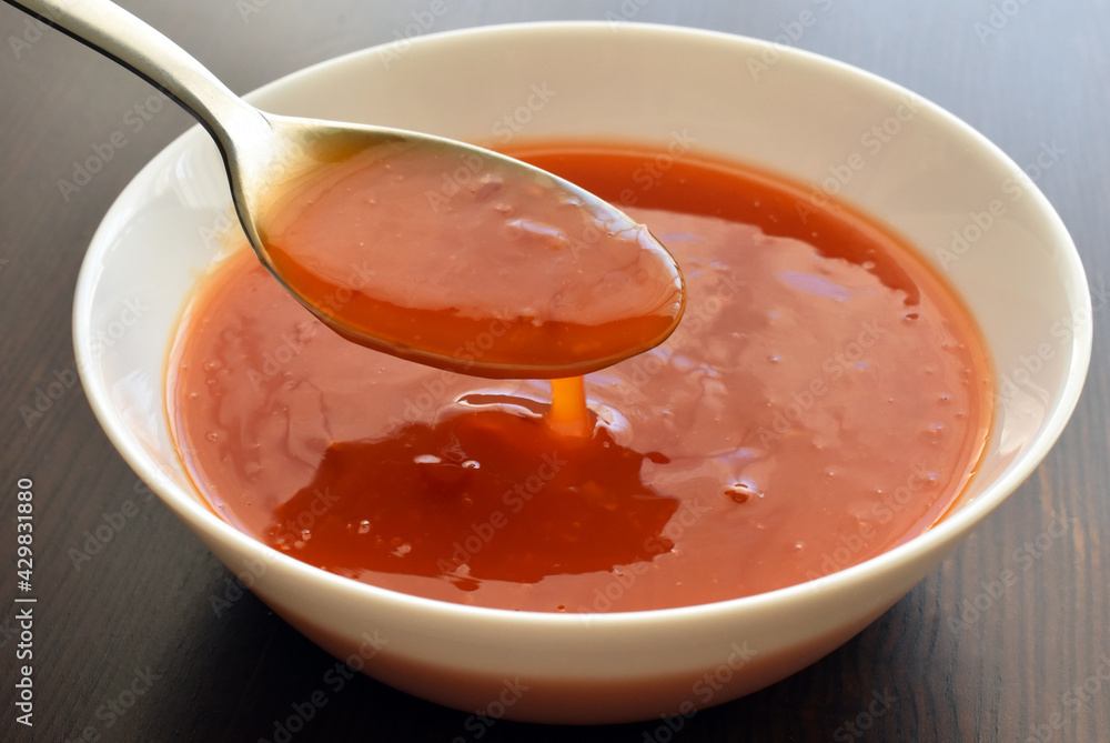 Sweet chilli sauce on spoon on a white bowl. Sweet chilli sauce on spoon on a white bowl.