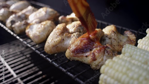 Slow motion shot of bbq sauce being brushed on smoking grilled chicken