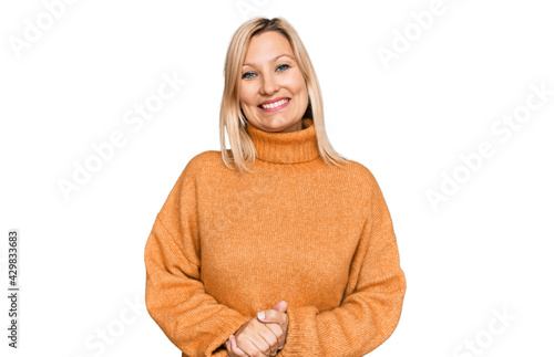 Middle age caucasian woman wearing casual winter sweater with hands together and crossed fingers smiling relaxed and cheerful. success and optimistic