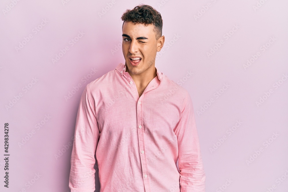 Hispanic young man wearing casual clothes winking looking at the camera with sexy expression, cheerful and happy face. Hispanic young man wearing casual clothes winking looking at the camera with sexy expression, cheerful and happy face.