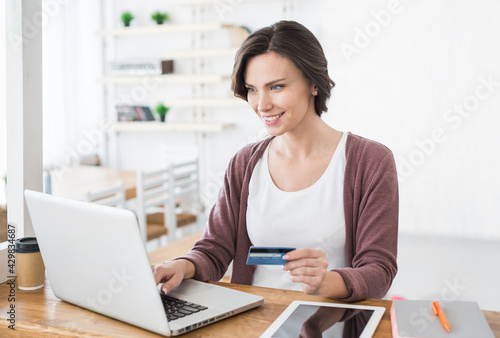 Young woman holding credit card and using laptop computer at home, Businesswoman or entrepreneur working, Online shopping, e-commerce, internet banking, spending money concept