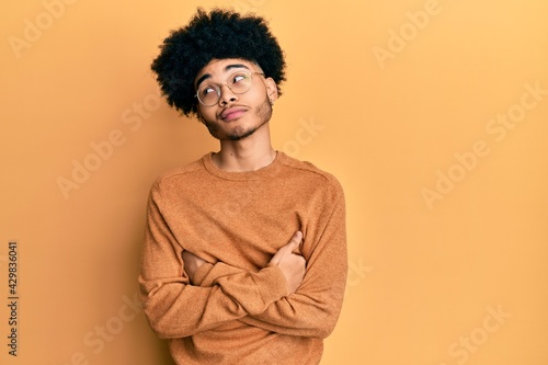 Young african american man with afro hair wearing casual winter sweater smiling looking to the side and staring away thinking. © Krakenimages.com
