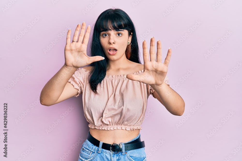 Young hispanic girl wearing casual clothes afraid and terrified with fear expression stop gesture with hands, shouting in shock. panic concept. Young hispanic girl wearing casual clothes afraid and terrified with fear expression stop gesture with hands, shouting in shock. panic concept.