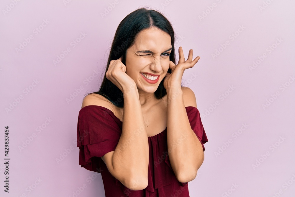 Young hispanic woman wearing casual clothes covering ears with fingers with annoyed expression for the noise of loud music. deaf concept. Young hispanic woman wearing casual clothes covering ears with fingers with annoyed expression for the noise of loud music. deaf concept.