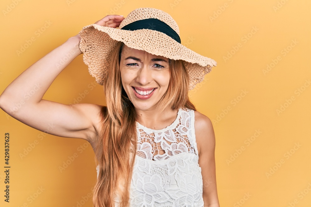 Young caucasian woman wearing summer hat confuse and wonder about question. uncertain with doubt, thinking with hand on head. pensive concept. Young caucasian woman wearing summer hat confuse and wonder about question. uncertain with doubt, thinking with hand on head. pensive concept.