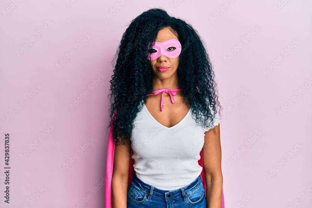 Middle age african american woman wearing super hero costume relaxed with serious expression on face. simple and natural looking at the camera.