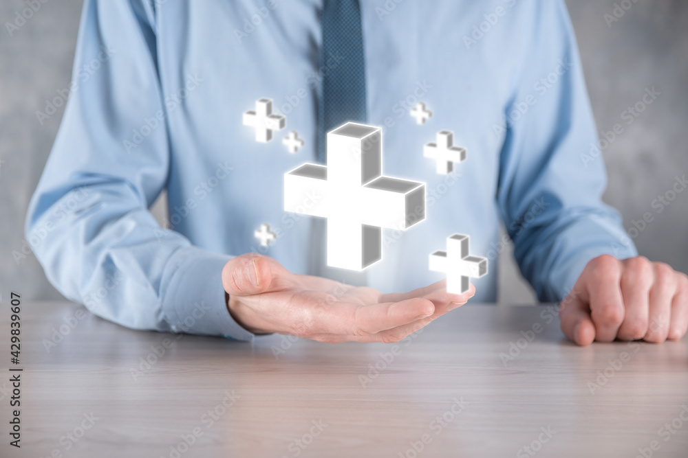 Businessman hold 3D plus icon, man hold in hand offer positive thing such as profit, benefits, development, CSR represented by plus sign.The hand shows the plus sign Businessman hold 3D plus icon, man hold in hand offer positive thing such as profit, benefits, development, CSR represented by plus sign.The hand shows the plus sign