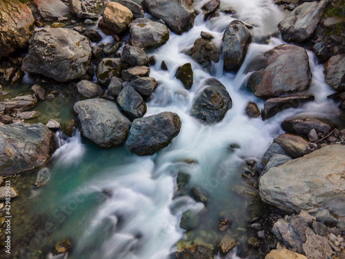 Aerial long exposure of alpine river in the mountain, silk effect, flowing water