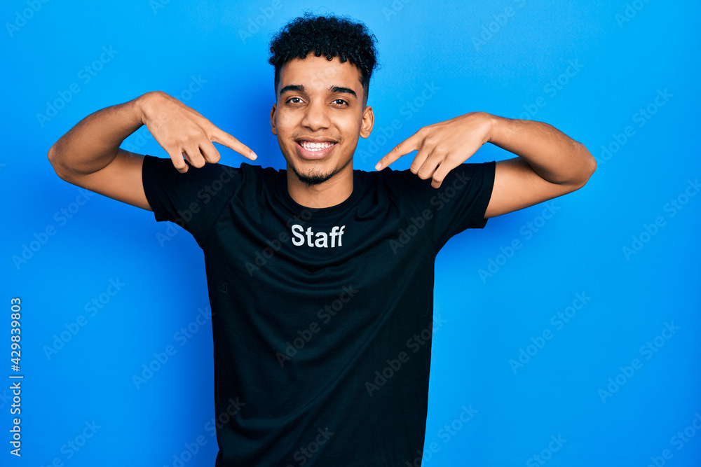 Young african american man wearing staff t shirt smiling cheerful showing and pointing with fingers teeth and mouth. dental health concept. Young african american man wearing staff t shirt smiling cheerful showing and pointing with fingers teeth and mouth. dental health concept.