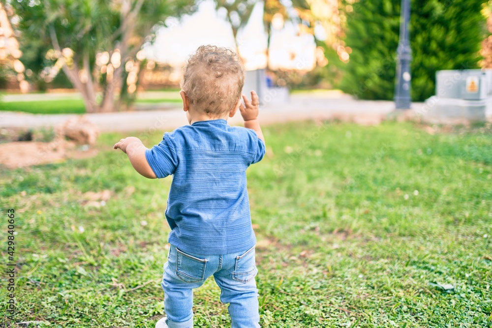 Cute and happy little boy having fun at the park on a sunny day. Beautiful blonde hair male toddler playing outdoors Cute and happy little boy having fun at the park on a sunny day. Beautiful blonde hair male toddler playing outdoors