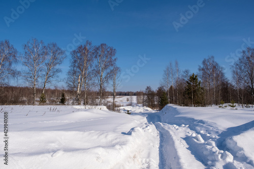 Snow-covered rural road on a frosty winter cloudless and sunny day.