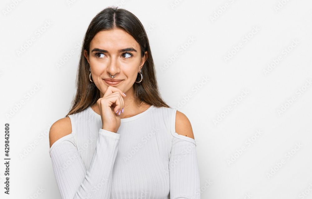 Young hispanic woman wearing casual clothes with hand on chin thinking about question, pensive expression. smiling with thoughtful face. doubt concept. Young hispanic woman wearing casual clothes with hand on chin thinking about question, pensive expression. smiling with thoughtful face. doubt concept.