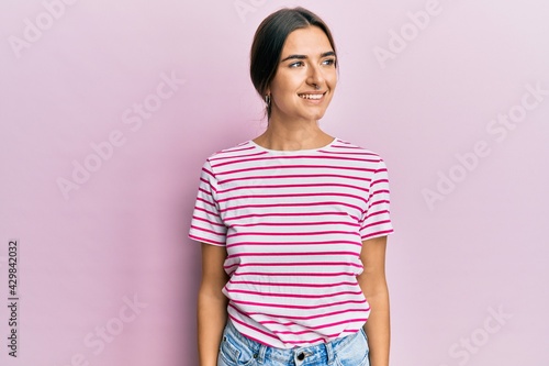 Young hispanic woman wearing casual clothes looking to side, relax profile pose with natural face and confident smile.