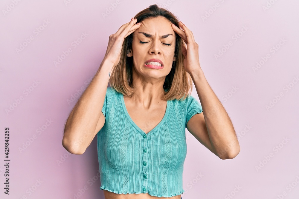 Young caucasian blonde woman wearing casual blue t shirt with hand on head, headache because stress. suffering migraine. Young caucasian blonde woman wearing casual blue t shirt with hand on head, headache because stress. suffering migraine.