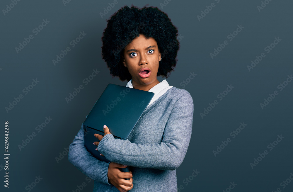 Young african american woman working using computer laptop in shock face, looking skeptical and sarcastic, surprised with open mouth Young african american woman working using computer laptop in shock face, looking skeptical and sarcastic, surprised with open mouth